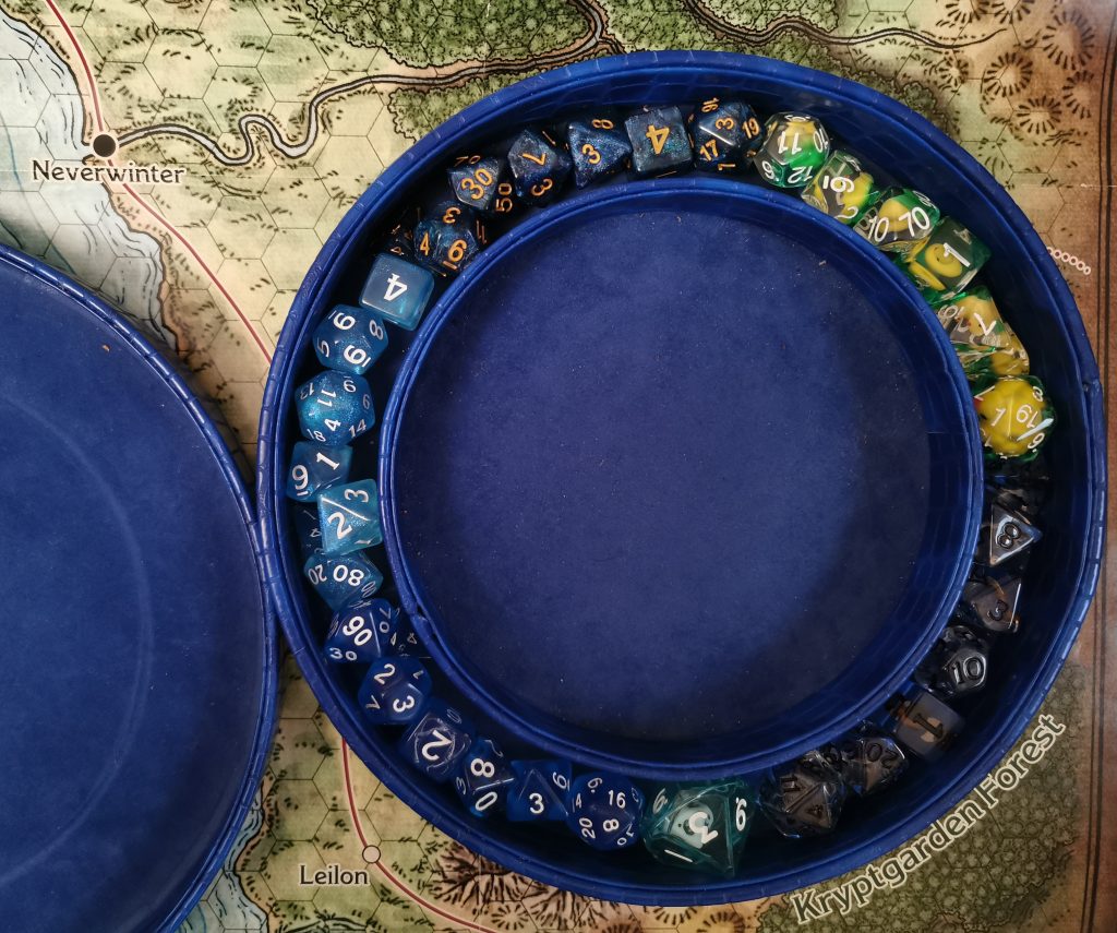 A circular blue dice tray containing several sets of rpg dice, placed on a map of the Sword Coast from D&D 5E
